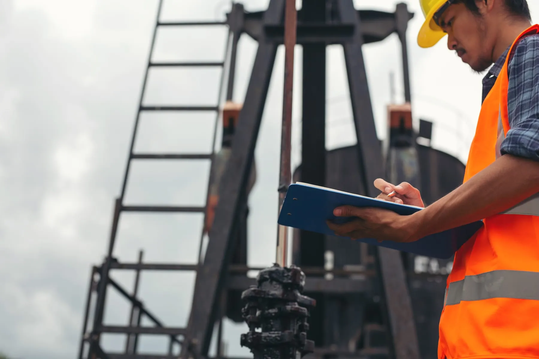Workers standing checking beside working oil pumps